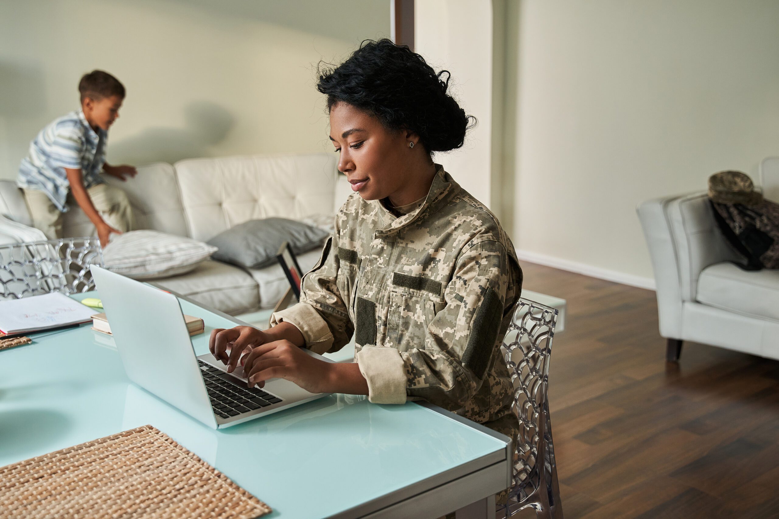 Black woman soldier using laptop at table
